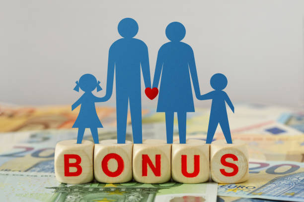 Paper family silhouette on wooden blocks with the word Bonus on euro banknotes - Concept of economic bonus and financial aid stock photo