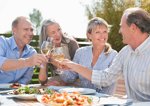 couple senior portant un toast verres à vin sur table du patio - dining senior adult friendship mature adult photos et images de collection