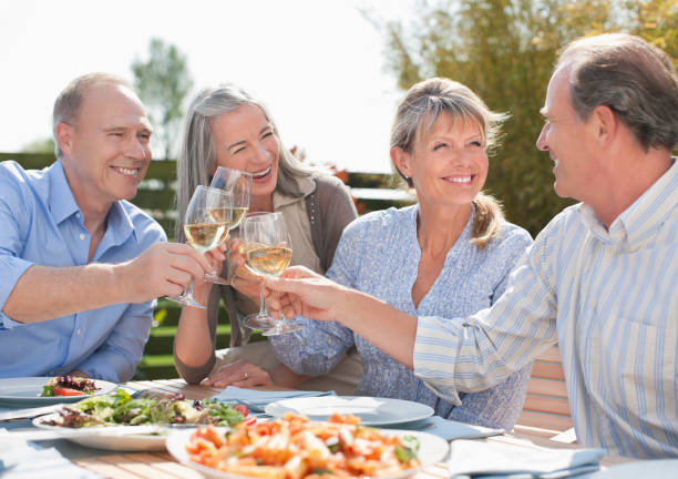 starsze pary opiekania wina szklanki na stół na patio - dining senior adult friendship mature adult zdjęcia i obrazy z banku zdjęć