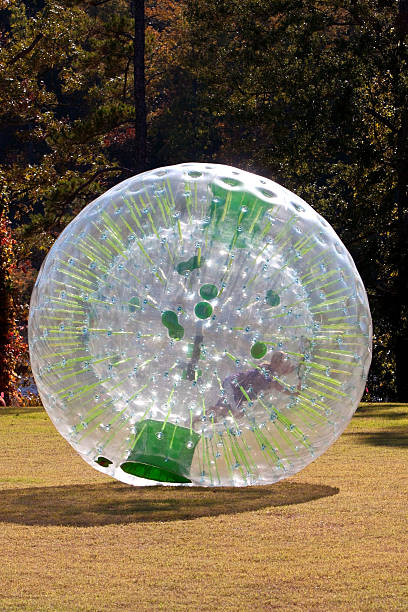 Kid Rolling Inside Large Plastic Ball Kid pushes and rolls inside large plastic ball (zorb). zorbing stock pictures, royalty-free photos & images