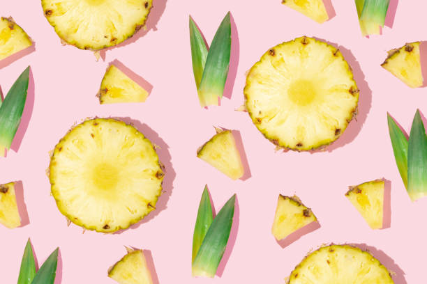 istock Creative pattern made with pineapple slices and green leaves on pastel pink background. Minimal flat lay. Creative idea with fruits. Spring or summer concept. 1370873741