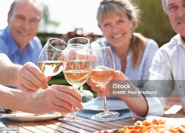 Ritratto Di Coppia Anziana Sorridente Brindando Con Vino Bicchieri Al Tabl - Fotografie stock e altre immagini di Vino bianco