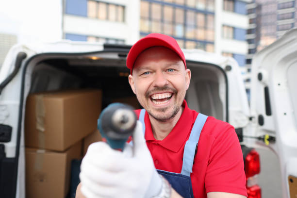 istock Happy courier in a red uniform shows a tool near a covered van 1370876308
