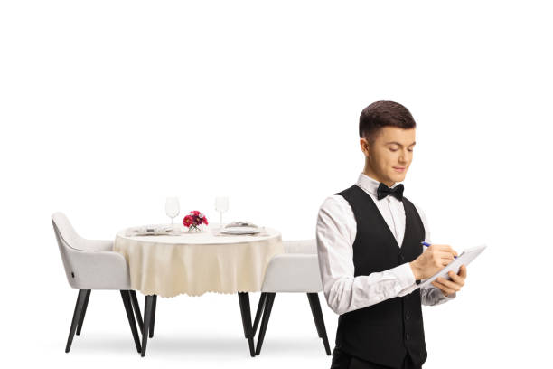 istock Waiter with a bow tie in front of a restaurant table 1370876339
