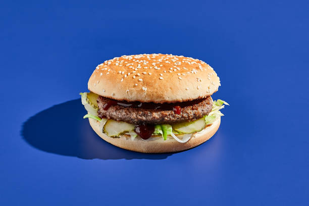 istock Beef burger blue background with hard shadow. American junk food minimal style. Hamburger trendy style.  Simple burger colour background. 1370877460