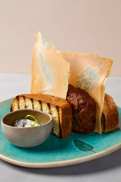 istock Bread dish with organic butter on blue ceramic plate. Artisan bread from chef. Contemporary baking. Homemade ceramic in modern style. Modern serveware on gray stone background. 1370877472