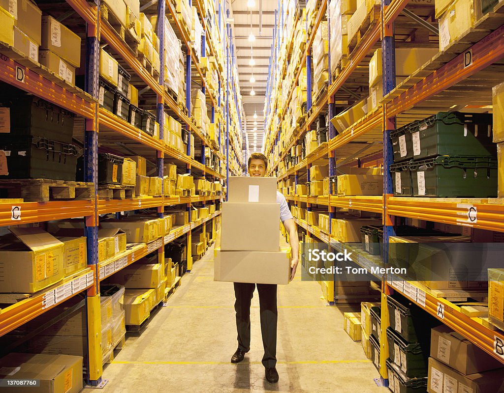 Worker carrying boxes in warehouse  Warehouse Stock Photo