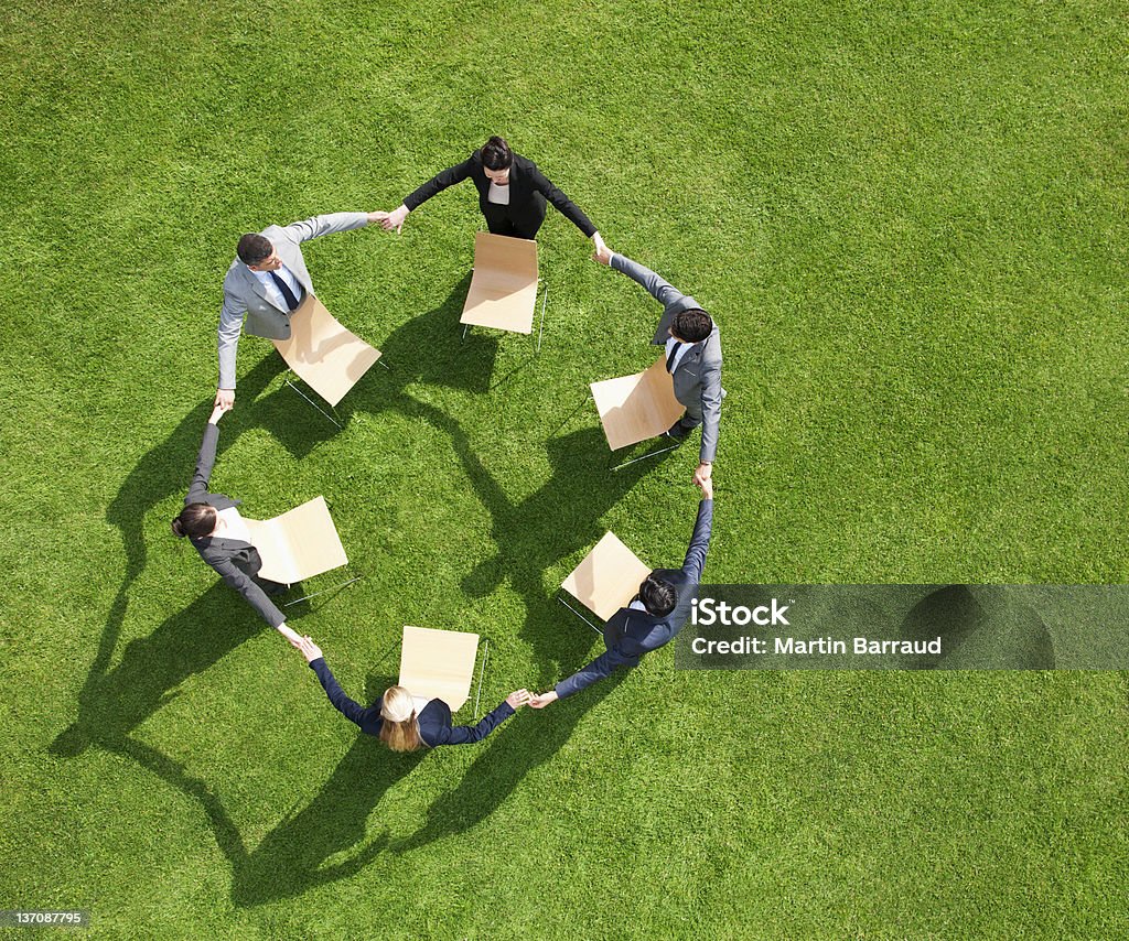 Business people holding hands in circle outdoors  Environmental Issues Stock Photo