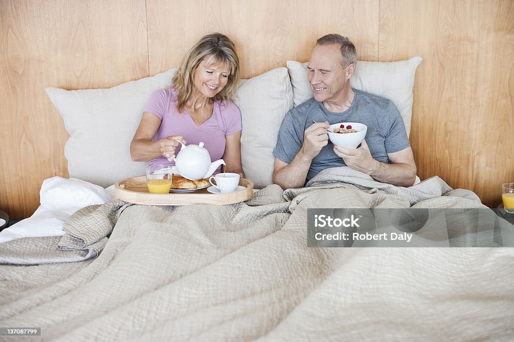 Coppia Senior mangiare la colazione a letto - Foto stock royalty-free di Letto