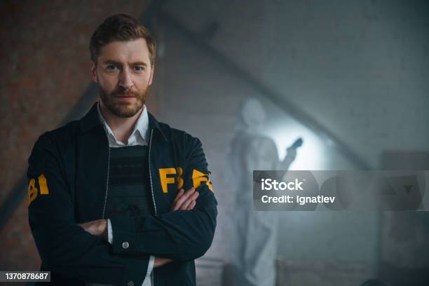 Handsome Fbi Agent Standing With His Arms Crossed At The Crime Scene He Looks At Camera We See Him From The Waist Up Stock Photo - Download Image Now