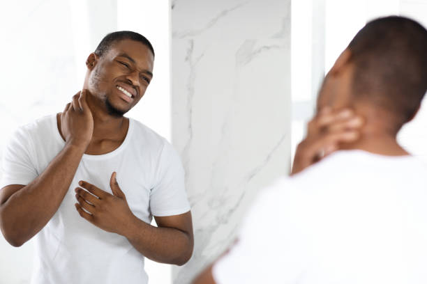 istock Unhappy Black Guy Suffering Neck Ache While Standing Near Mirror In Bathroom 1370880074