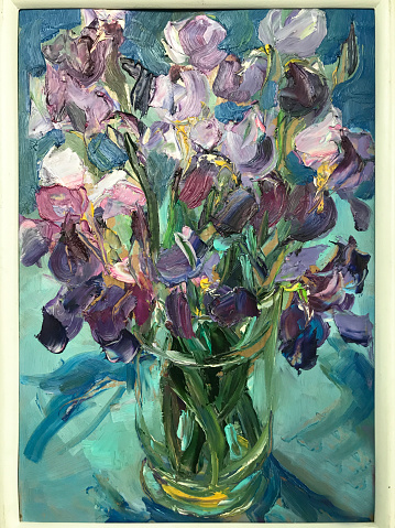 Oil paints, expressive strokes on canvas. Vertical painting in a frame, art work in the gallery. Gorgeous flower still life. Spring or summer flowering plants, bloom. Purple irises in transparent vase