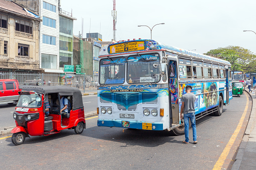 Kandy, Sri Lanka - February 13, 2020: Bus and tuk tuk on the street in Colombo
