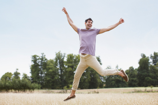 Cheerful man walking with arms outstretched in nature on beautiful spring day.