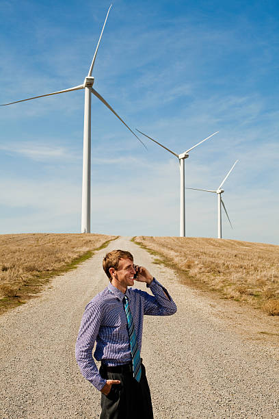 homme à l'aide de téléphone mobile dans le vent turbines - dry white blue northern california photos et images de collection