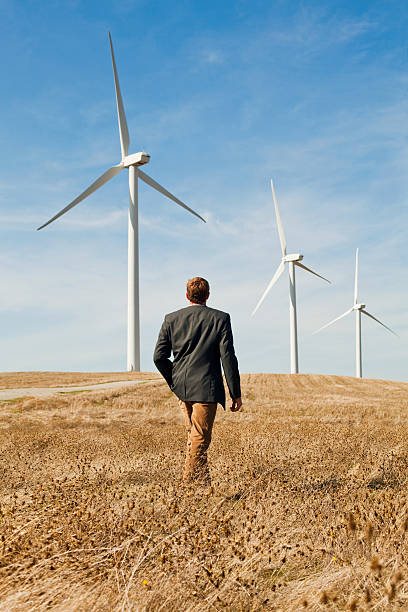 hombre caminando en frente de turbinas eólicas - wind turbine motion alternative energy wind power fotografías e imágenes de stock