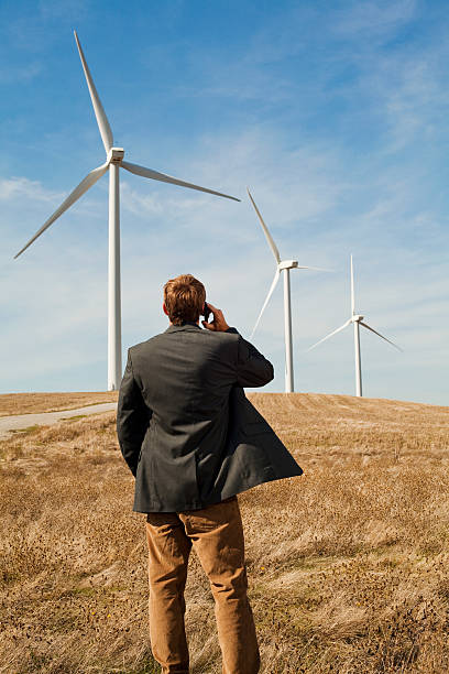 homme debout en face de turbines de vent sur téléphone mobile - dry white blue northern california photos et images de collection