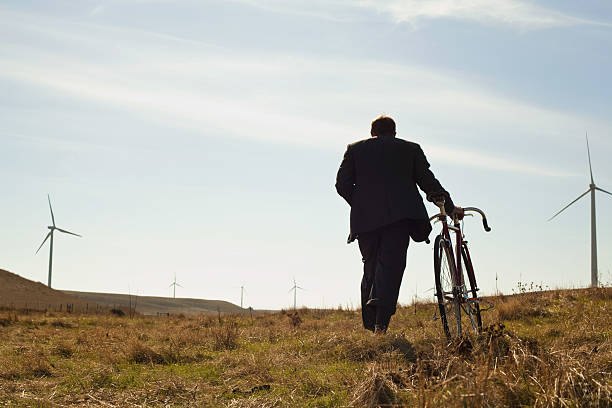 bicicleta hombre tirando hacia windfarm arriba - wind turbine motion alternative energy wind power fotografías e imágenes de stock