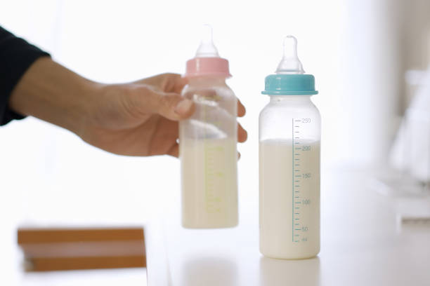 Asian man giving milk to twin babies Asian man giving milk to twin babies baby bottle stock pictures, royalty-free photos & images