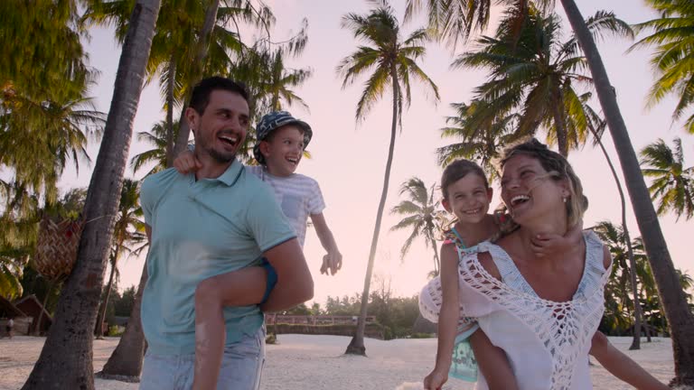 Carefree family having fun while piggybacking on the beach.