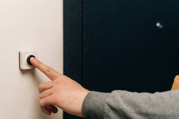 doigt rapproché d’un homme méconnaissable poussant le bouton de la sonnette dans l’entrée de l’immeuble. vendeur, invité ou visiteur derrière la porte. - sonner photos et images de collection