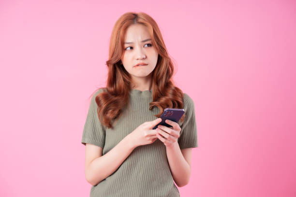 istock Young Asian woman using smartphone on pink background 1370887963