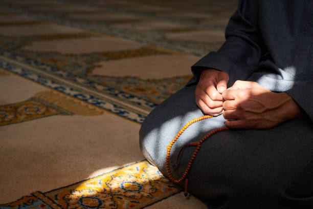 istock Close up of hands holding prayer beads in a mosque with sunlight 1370888152