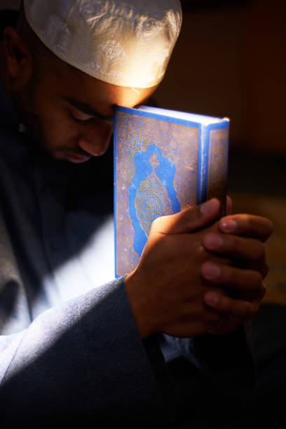 istock Hands hold the Quran bathed in sunlight inside a mosque 1370888247