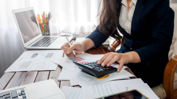 femme d’affaires travaillant dans la finance avec calculatrice au bureau. - bureaucracy photos et images de collection