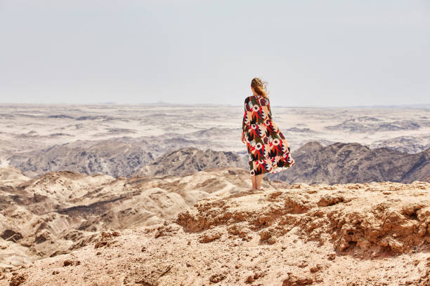 una donna in un bel vestito si trova di fronte a un paesaggio lunare in vacanza - erongo foto e immagini stock