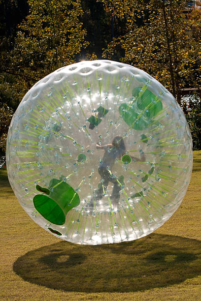 Girl Rolling Inside Large Plastic Ball A girl pushes and rolls from inside plastic ball (zorb). zorbing stock pictures, royalty-free photos & images