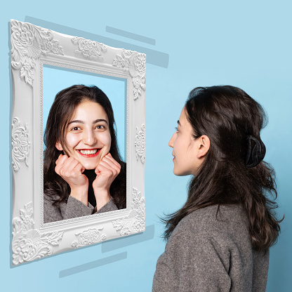 Happy or sad. Young girl looking in mirror at her own reflection. The spectrum of human emotions. Bipolar disorder. Art collage. Concept of emotions, inner world, mental health, split personality