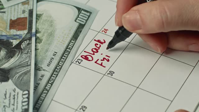 Woman hand marking the day in calendar by writing BLACK FRIDAY as a reminder using a black pen