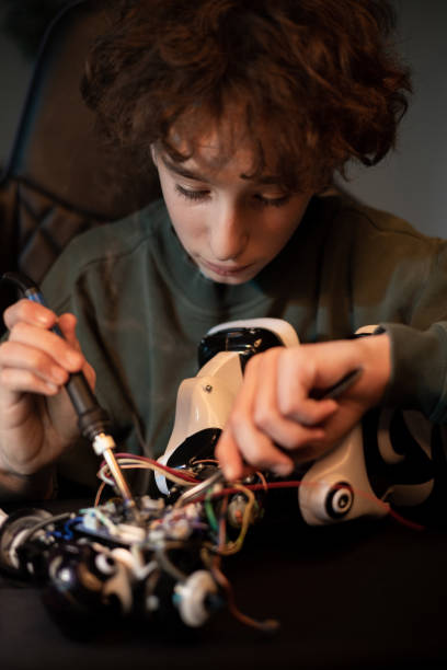 istock Electronics enthusiast spends time at home at desk digging into the robot's power cables, pulling out wires with a tweezers and soldering them 1370893065