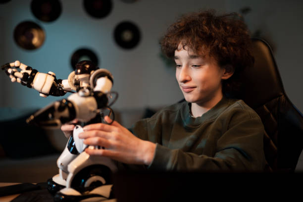 istock Young school-age boy spends time in room at desk, child in curly-haired sweatshirt assembles robot, builds toy, develops passion for electronics 1370893232