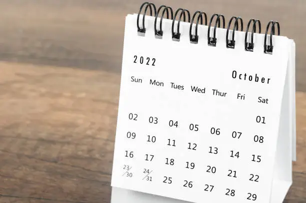 The October 2022 desk calendar on wooden background.