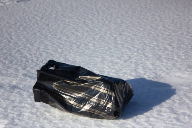 istock Black bag in the snow. Plastic bag on the snow close-up. 1370896302