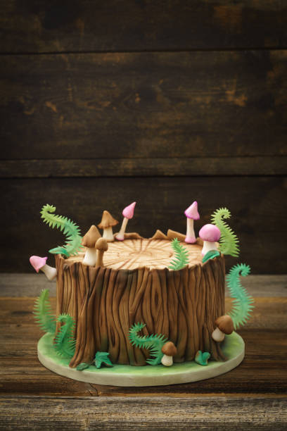 Enchanted forest cake Enchanted forest woodland themed fondant cake with a tree trunk, ferns, mushrooms and leaves on wooden background with copyspace birthday cake green stock pictures, royalty-free photos & images