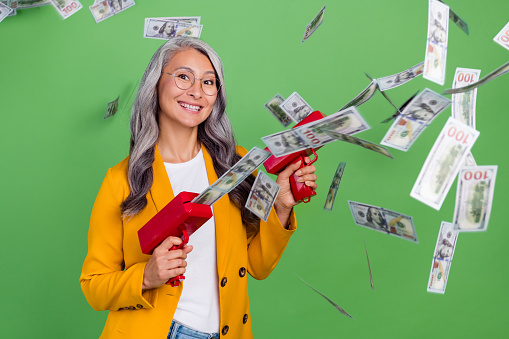 Photo of cheerful lovely woman good mood spent money wealthy win lottery isolated over green color background.