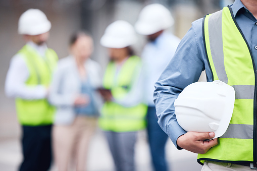 Multiethnic diverse group of engineers or business partners at construction site, working together on building's blueprint, architect industry or teamwork concept.