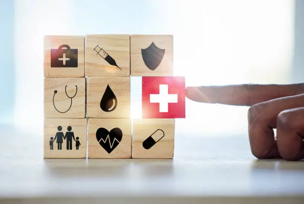 Photo of Shot of an unrecognisable man assembling building blocks with medical icons on them