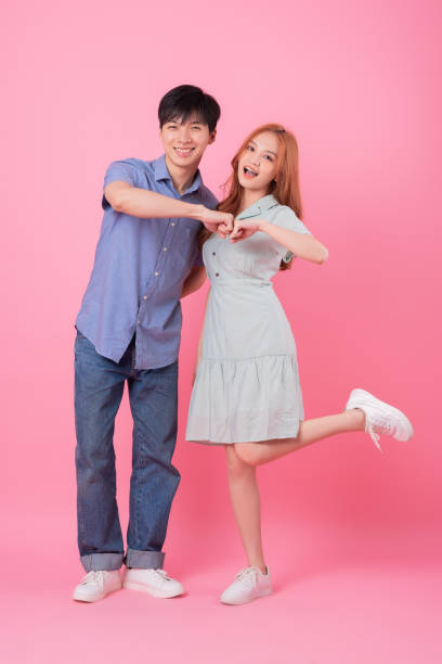 istock Young Asian couple posing on pink background 1370902273