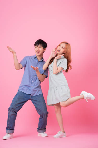 istock Young Asian couple posing on pink background 1370902274
