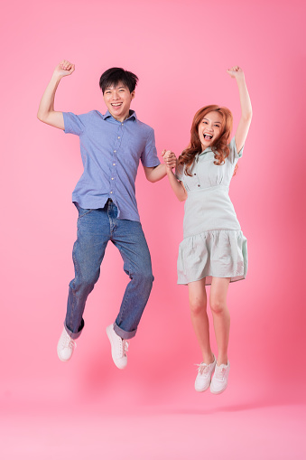 Young Asian couple posing on pink background