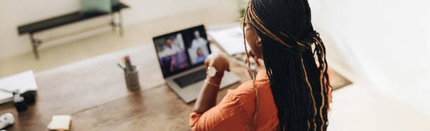 female designer attending a virtual meeting - wide imagens e fotografias de stock