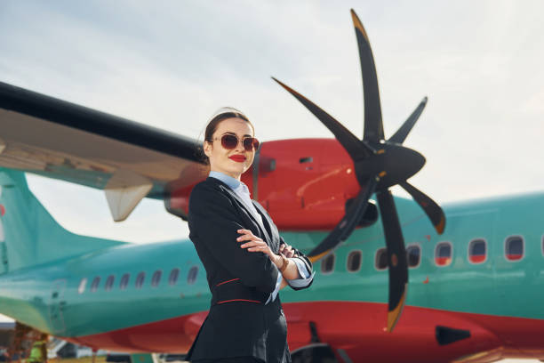istock Young stewardess that is in formal black clothes is standing outdoors near plane 1370906910