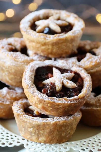 istock Full frame image of white cake stand containing batch homemade mince pies dusted with icing sugar, illuminated fairy lights background, focus on foreground 1370907089