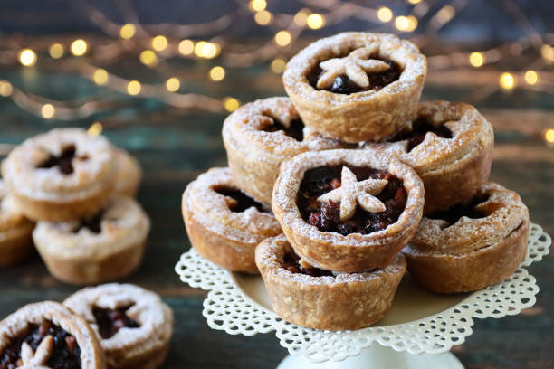 imagem de close-up de suporte de bolo branco contendo em lote tortas caseiras de menta empoeiradas com açúcar de confeiteiro, fundo de luzes de fada iluminadas, foco em primeiro plano - currant food photography color image - fotografias e filmes do acervo