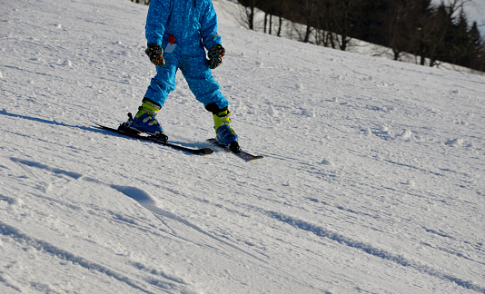little boy skiing in the snow with a plow style. Tyrolean skiing styles are simple and safe. ski kindergarten for children