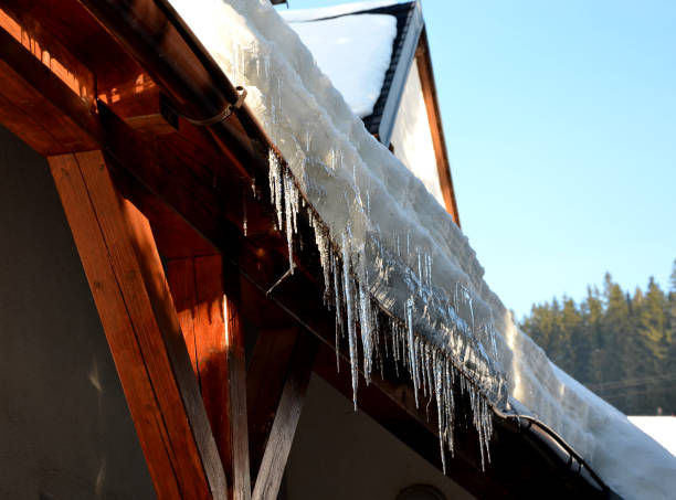 il calore della casa passa attraverso il tetto e scioglie la neve. si congela nella grondaia del tetto e forma ghiaccioli. l'isolamento del traliccio di repel deve essere eseguito - snow bound foto e immagini stock